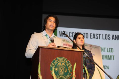 Young man speaking at podium with young woman